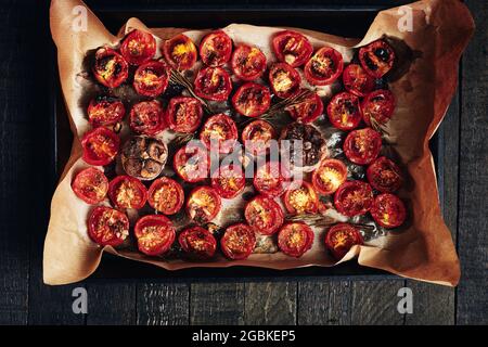 Ofengeröstete Kirschtomaten auf einem Ofenblech. Ansicht von oben. Stockfoto