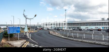 Außenansicht und Eingang zum Flughafen Glasgow Prestwick, Schottland, mit der Statue Celetial Navigator (1997) von Carole Grey, Multilingual Road sign. Stockfoto