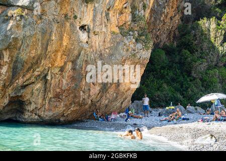 Panoramablick auf Foneas Strand überfüllt mit Touristen und Schwimmern. Der felsige Strand befindet sich in der Küstenregion Mani in der Nähe des Dorfes Kardamyli in M Stockfoto