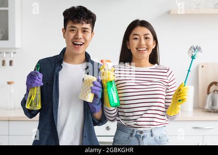Portrait eines positiven asiatischen Paares, das Reinigungswerkzeuge hält Stockfoto
