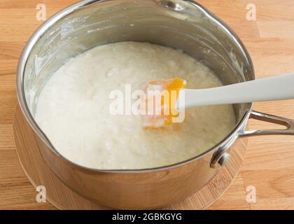 Koche in einer Pfanne köstlichen Reisbrei. Silikonspachtel. Stockfoto