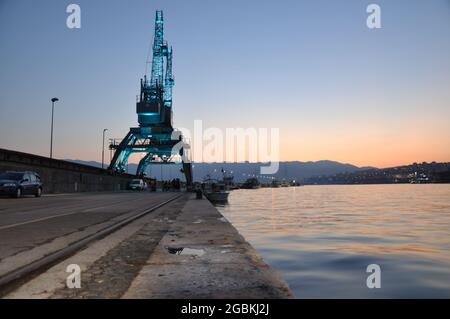 Nachtfoto von Strandpromenade und leichten Kränen im Hafen Rijeka in Kroatien, Reflexion Stockfoto