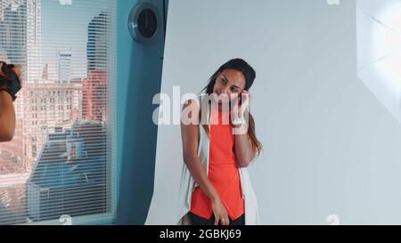 Attraktives Modemodell afrikanischer Ethnie, das sich für einen Fotografen ausstellt, der mit einer professionellen Kamera fotografiert. Stockfoto