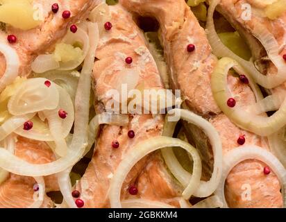 Gebackene Forellenstücke mit Zwiebeln, Kartoffeln und rosa Paprika, Hintergrund Stockfoto