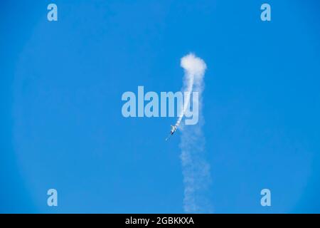 Stund Plane macht eine Schleife mit Rauch in türkisblauem Himmel. Stockfoto