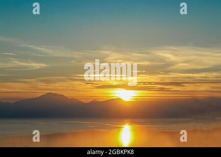 Dramatischer Sonnenuntergang, der sich im Wasser über dem Golf von Korinth auf dem griechischen Festland spiegelte, führte von Westen aus die Berge in Richtung Delphi hinauf Stockfoto