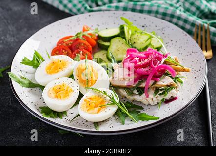 Frühstück. Gekochter Eiersalat mit Gemüse, Gurken, Tomaten und Sandwich mit Ricotta-Käse, gebratenem Hühnerfilet und roter Zwiebel. Keto/Paleo Mittagessen. Stockfoto