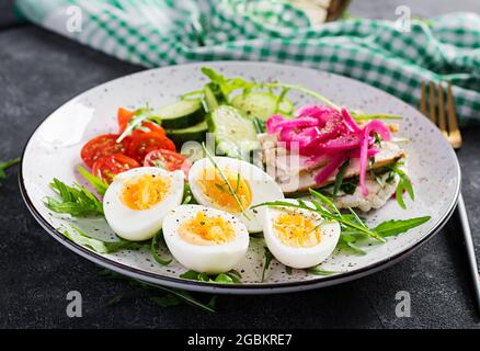 Frühstück. Gekochter Eiersalat mit Gemüse, Gurken, Tomaten und Sandwich mit Ricotta-Käse, gebratenem Hühnerfilet und roter Zwiebel. Keto/Paleo Mittagessen. Stockfoto