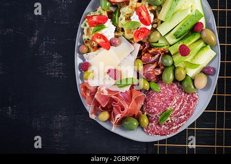 Charcuterie-Board. Platte: parmesan mit Prosciutto, Salami, Gurken und Oliven. Auswahl an leckeren Vorspeisen oder Antipasti. Draufsicht, Kopierbereich, Stockfoto