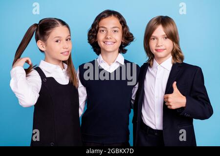 Foto Porträt Schulkameraden lächeln in Uniform zeigen Daumen-up-Zeichen isoliert pastellblau Hintergrund Stockfoto