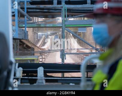 Heilbronn, Deutschland. August 2021. Die baden-württembergische Umweltministerin Thekla Walker (r, Bündnis 90/die Grünen) schaut sich während ihres Rundgangs durch das Salzbergwerk Heilbronn die Bergbau- und Förderbänder in einem Stollen an. Die Tunnel der Südwestdeutschen Salzwerke spielen unter anderem bei der Lagerung gefährlicher Abfälle eine wichtige Rolle. Quelle: Bernd Weißbrod/dpa/Alamy Live News Stockfoto