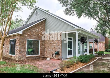 Eine schräge Vorder- und Seitenansicht eines akadischen renovierten Hauses mit Säulen, Gehwegen und einer farbenfrohen Eingangstür, die kürzlich gekauft wurde Stockfoto