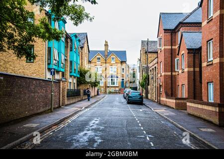 Oxford UK Straße mit Autos geparkt und hohe Gebäude auf beiden Seiten und nassen Bürgersteig und junge können mit Rucksack zu Fuß auf Bürgersteig - Schild liest Ric Stockfoto