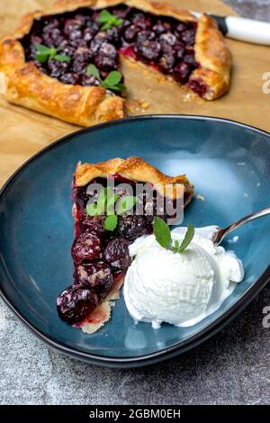 Sommergalette mit Kirschen auf grauem Betongrund. Sommerkuchen. Stockfoto