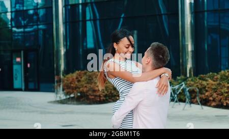 Das multiethnische Paar verbringt gern gemeinsam Zeit im Zentrum der Großstadt. Mann hält Frau in den Armen und dreht sich um. Stockfoto
