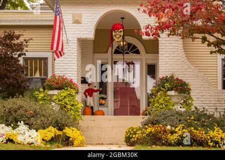 Ziemlich traditioneller Hauseingang im Herbst mit wunderschöner Landschaft und Blumen und einem Keramikjockey vor der Haustür mit Halloween-Dekorationen und einem Stockfoto