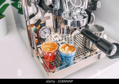 Zwei Macchiato-Shots in Espressotassen auf der Kaffeemaschine zu Hause - weiße Wohnküche, moderner Interieur-Lifestyle Stockfoto