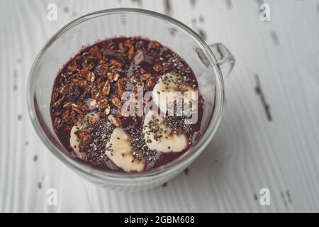 Acai Smoothie Frühstückschüssel mit frisch geschnittenen Bananen Belag auf gefrorenen Beeren schütteln. Gesundes Bio-Frühstück Blick von oben zu Hause Stockfoto