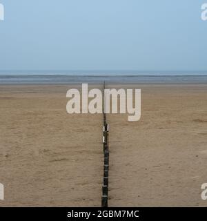 Eine hölzerne Erosionskontrolle teilt den Strand von Brean Sands an der Küste des Bristol Channel in Somerset. Stockfoto