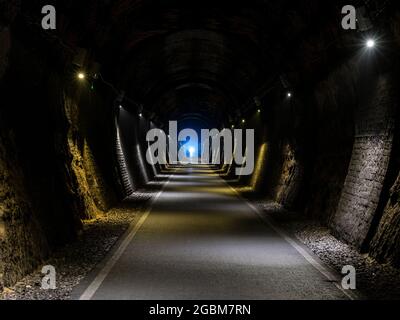 Im dunklen Combe Down Tunnel, Teil der beiden Tunnel Greenway Rail Trail in Bath, Somerset, leuchtet ein Radfahrerscheinwerfer. Stockfoto