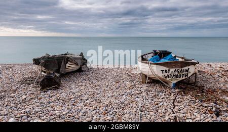 Weymouth, England, Großbritannien - 13. Februar 2010: Kleine Fischerboote werden auf den Kieselsteinen des Chesil Beach in Chiswell an der Jurassic Coast von Dorset befahren. Stockfoto