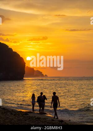 Silhouetten von Menschen an einem Strand in Bali bei goldenem Sonnenuntergang Stockfoto