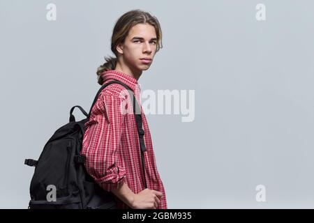 Guy Student Teenager mit Rucksack Blick auf die Kamera auf hellen Hintergrund Stockfoto