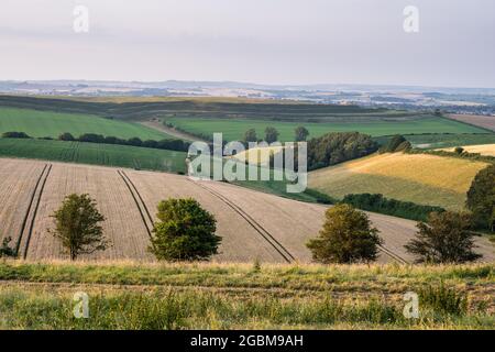 Die Festung Maiden Castle aus der Eiszeit erhebt sich zwischen den sanften Hügeln der Dorset Downs in der Nähe von Dorchester. Stockfoto