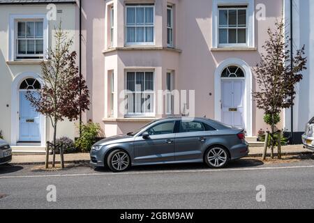 Straßenbäume markieren Parkplätze auf der Straße vor den neu erbauten Häusern in der neuen Stadt Poundbury, Dorset. Stockfoto