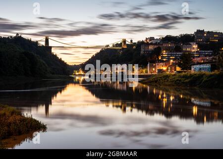 Die Sonne untergeht hinter der berühmten Clifton Suspension Bridge, der Stadtlandschaft von Hotwells und der River Avon Gorge in Bristol, England. Stockfoto