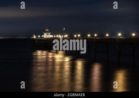 Ein Halbmond untergeht über dem Bristol Channel und dem Clevedon Pier in Somerset, England. Stockfoto