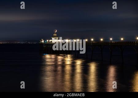 Ein Halbmond untergeht über dem Bristol Channel und dem Clevedon Pier in Somerset, England. Stockfoto