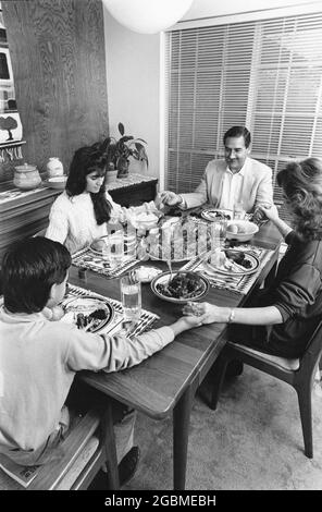 Austin Texas USA, 1990: Hispanische Familie hält die Hände fest und betet zusammen, bevor sie zu Hause am Sonntag zu Abend essen. MR es-0506 Farbe erhältlich. ©Bob Daemmrich Stockfoto