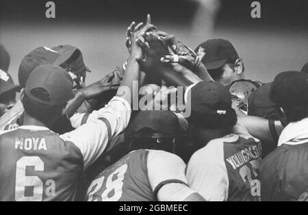 Austin, Texas, USA, um 1989: Mitglieder des College-Baseballteams treffen sich auf dem Spielfeld und teilen sich High-Five-Titel, um den Sieg zu feiern. ©Bob Daemmrich Stockfoto