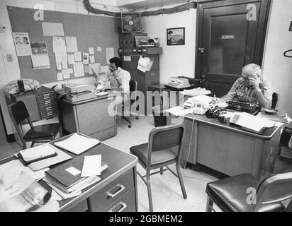 Austin, Texas, USA, um 1982: Männliche Mitarbeiter, die in ein kleines Büro eingepfercht sind, zeigen überfüllte Arbeitsbedingungen im Travis County Sheriff's Office. ©Bob Daemmrich Stockfoto