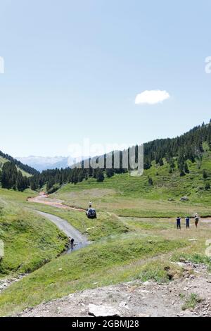 Landstraße durch die grünen Felder in den Bergen an einem sonnigen Tag Stockfoto