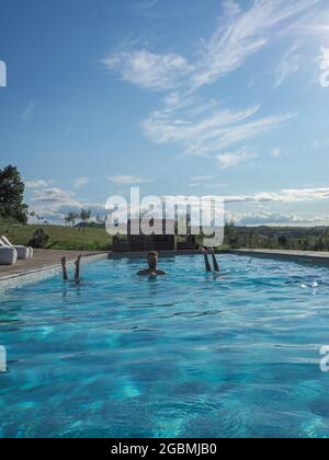 Vertikale Aufnahme eines kaukasischen Mannes im Pool mit zwei kopfüber stehenden Frauen an einem sonnigen Tag Stockfoto