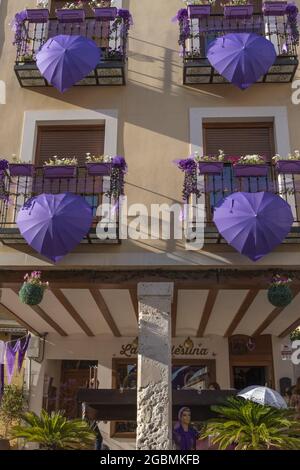 BRIHUEGA, SPANIEN - 10. Jul 2021: Eine Aufnahme von purpurnen Regenschirmen, die im Juli die Straßen von Brihuega schmücken Stockfoto