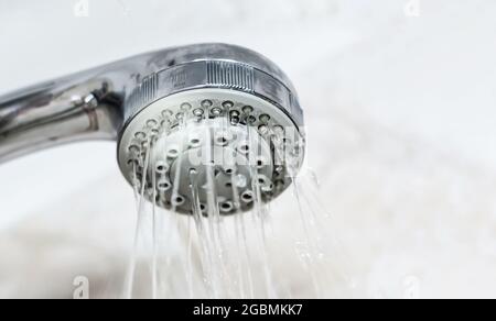 Das Innere einer Dusche mit Wasser, das aus dem Duschkopf fließt. Tröpfchen und Feuchtigkeit. Hygiene und Körperpflege Stockfoto