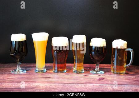 Sechs Gläser mit verschiedenen Biersorten auf einem Holztisch. Nahaufnahme. Stockfoto
