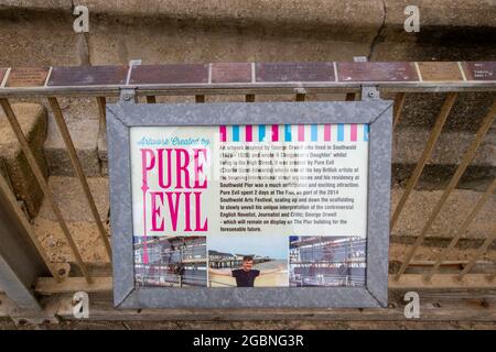 SOUTHWOLD, GROSSBRITANNIEN - 10. Aug 2016: Das Informationsschild über den Künstler Pure Evil am Southwold Pier in Suffolk Stockfoto