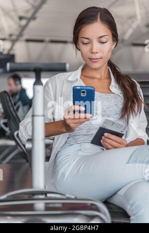 Flugpassagin eine chinesische Touristenfrau, die mit Handgepäck am Terminal auf verspäteten Flug wartet, um am Terminal telefonisch einzuchecken Stockfoto