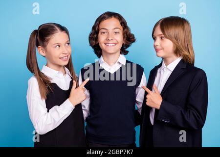 Foto Porträt Schulkameraden lächeln in Uniform zeigen Finger auf Freund isoliert pastellblau Hintergrund Stockfoto