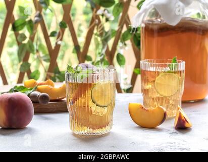 Hausgemachte Gärung. Kombucha-Tee leicht alkoholisches, leicht brausendes Getränk mit Pfirsich und Limette. Stockfoto