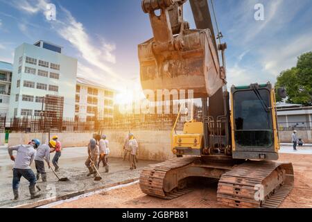 Bauarbeiter mit Bagger schwere Maschine und Zement-LKW für Betongießen während der gewerblichen Betonierung Böden im Gebäudebau si Stockfoto