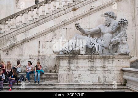 Eine monumentale Skulptur in der Nähe der Außentreppe auf der piazza vor den Kapitolinischen Museen. Mit ruhenden Touristen auf einer Bank in Rom, Italien. Stockfoto