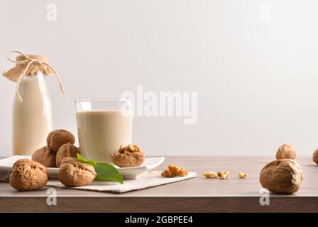 Glas und Flasche alternativen Gemüsegetränk Walnüsse mit Früchten auf Holztisch isoliert Hintergrund Stockfoto