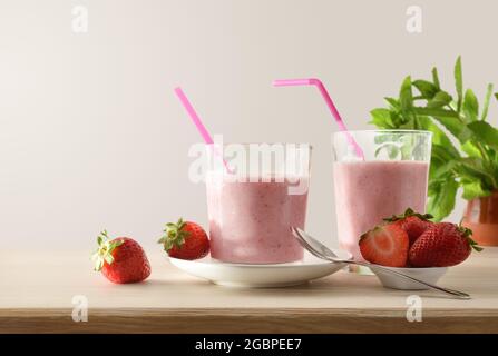 Gläser voller Erdbeer-Smoothie auf einem Holztisch voller Früchte isoliert Hintergrund. Vorderansicht. Stockfoto