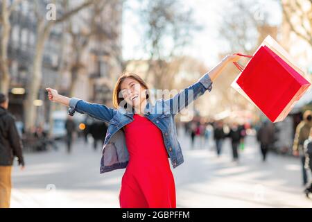 Herbst Mode Verkauf glückliche Frau zu Fuß mit Einkaufstaschen auf der La Rambla Straße in Barcelona. Shopper asiatische Mädchen ekstatisch mit offenen Armen halten Stockfoto