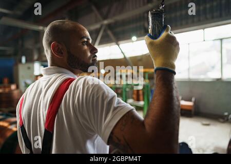 Techniker in Uniform mit Kransteuerung, die in einer Fabrik von der Decke hängt Stockfoto